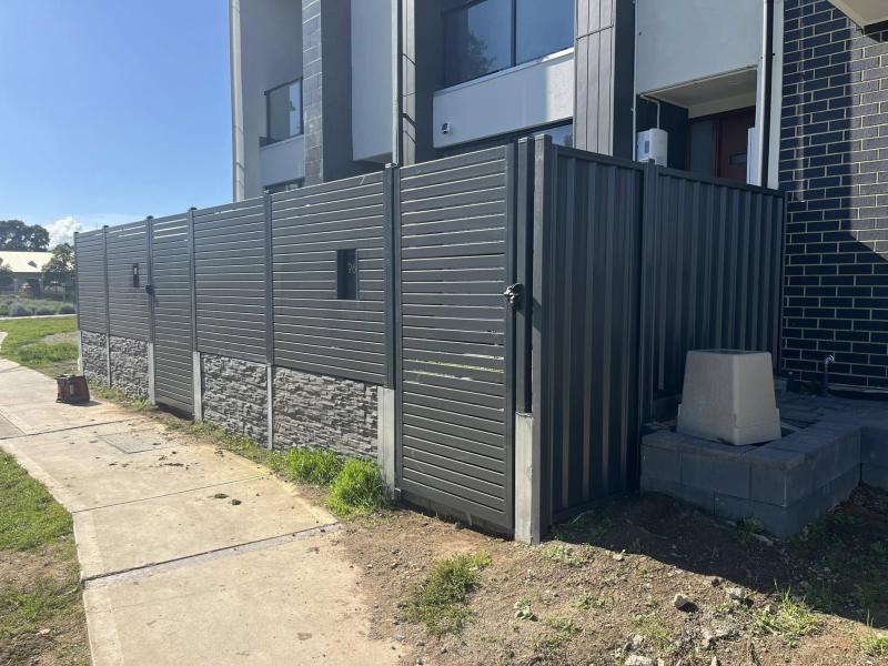 Aluminium slat fence and matching gate over a stone-look retaining base